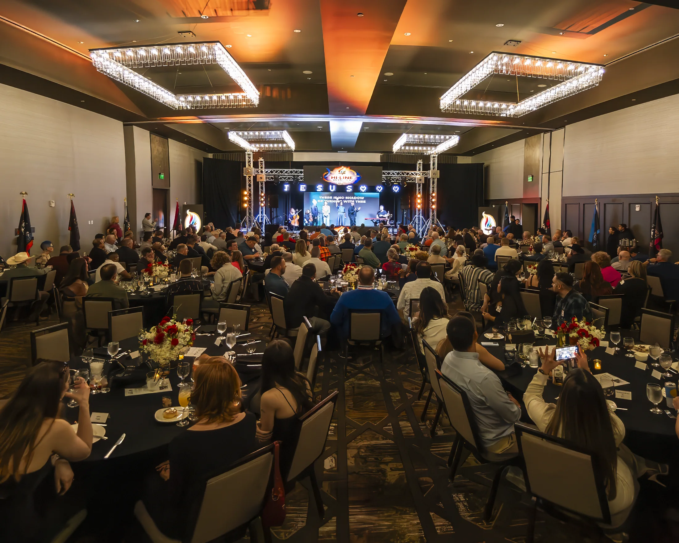 A packed conference room facing the illuminated Hi-Line Olympics stage