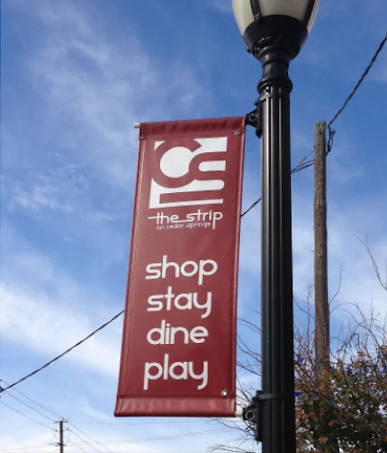 A single color street banner on a lamp post reading shop stay dine play